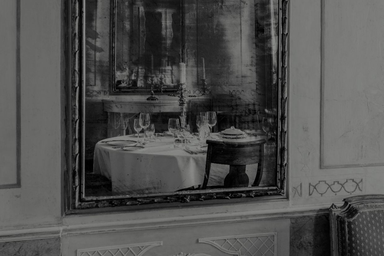 Black and white picture of a palatial room reflected in a mirror in Venice