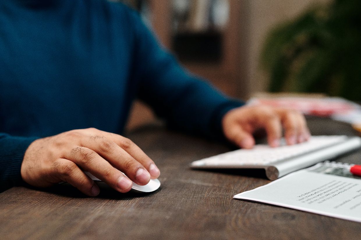 Close-up of hands using a computer keyboard and mouse